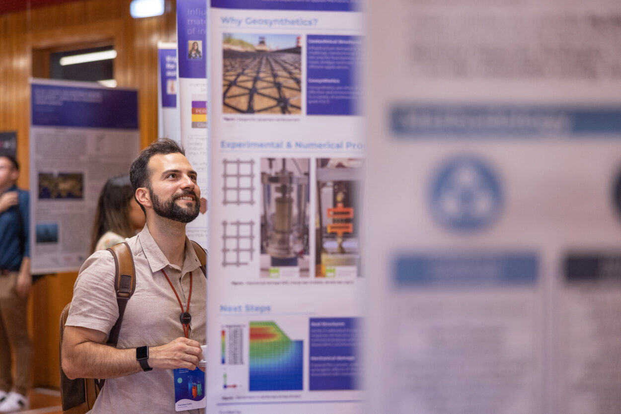 Man with beard smiles while reading a poster